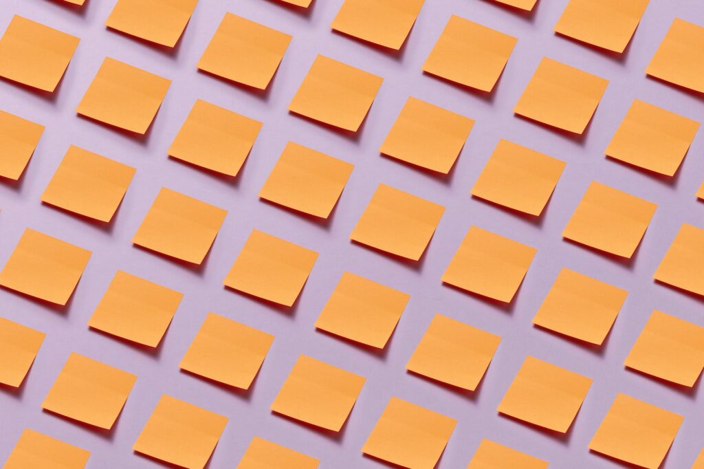 an array of blank orange notepads stuck on purple surface